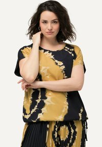 Krátký rukáv tričko s batikovaným vzorem v žluté a černé barvě s vířivými vzory, vyrobené z lehké tkaniny s volným střihem.