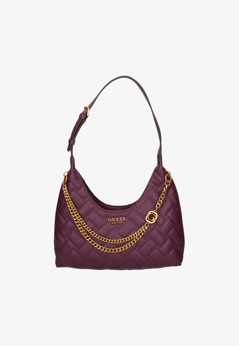 Fioletowa torebka pikowana z złotym akcentem łańcucha. Posiada zakrzywiony kształt i pojedynczy pasek, oznakowana "GUESS EST. 1981."