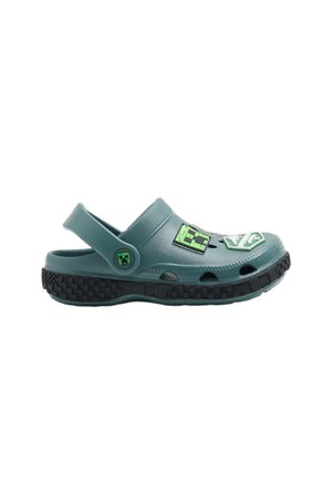 Afslappet grøn slip-on træsko med sort tekstureret sål, ventilationshuller, justerbar rem og pixelerede grønne kvadratudskæringer.