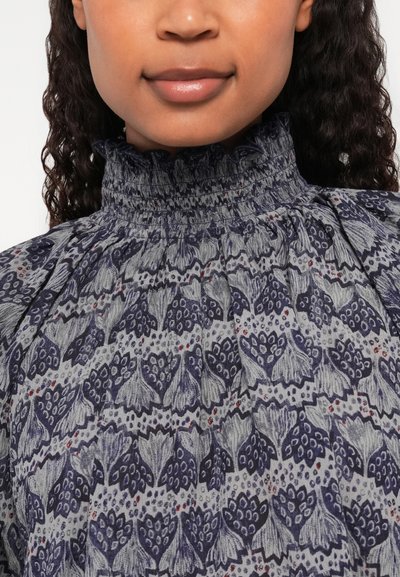 Tengerés virágmintás blúz, smockolt magas nyakkal és texturált anyaggal, bonyolult mintákkal és diszkrét piros részletekkel.