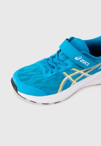 Τιρκουάζ αθλητικά παπούτσια με επάνω μέρος από δίχτυ, λευκές και πορτοκαλί λεπτομέρειες, επενδεδυμένο κολάρο και λαστιχένια σόλα για καλύτερο κράτημα. Περιλαμβάνουν κορδόνια και ρυθμιζόμενο λουράκι με αγκράφα hook-and-loop.