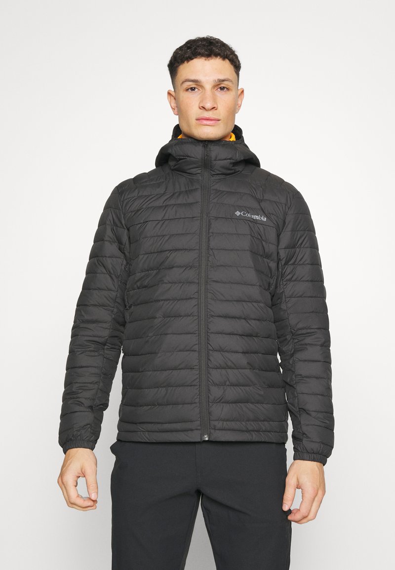 Svart puffjacka med huva, quiltad design, framdragkedja och elastiska ärmslut. Columbia-logotypen visas på övre vänstra sidan. Lätt material.
