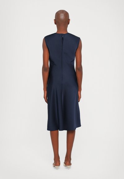 Rochie fără mâneci de culoare bleu marin, cu croială dreaptă, hem la genunchi și detaliu cu fermoar central la spate. Material neted, cu o textură ușor pronunțată.