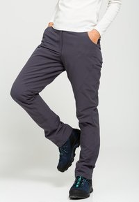 Grå utomhusbyxor med slim fit, tillverkade av lättviktig tyg, med sidofickor och subtila sömdetaljer. I kombination med svarta vandringsskor.