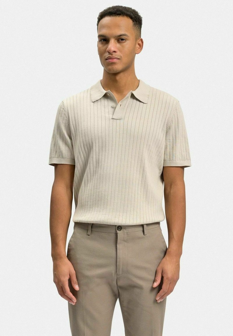 Beige randig pikétröja med korta ärmar, med en krage med två knappar, bärs med ljusbruna byxor. Slät textur, skräddarsydd passform.