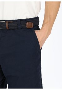 Navy blue, cotton pants with a smooth texture, featuring side pockets and a woven black belt with a brown leather accent.