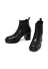 Botas de tobillo de cuero negro con paneles laterales elásticos, puntera redondeada y tacón cuadrado. Textura suave y diseño minimalista sin adornos.