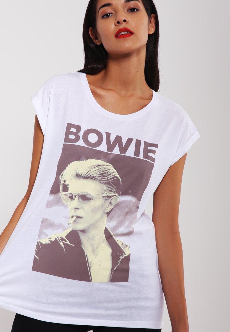 Valkoinen ylisuuri t-paita, jossa on graafinen printti miehestä, jolla on aurinkolasit ja savuke, ja jonka päällä on paksu ruskea teksti "BOWIE".