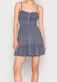 Šedé, lehké šaty s nastavovacími špagetovými ramínky, přiléhavým topem, detailem knoflíků a vrstvenou sukní s vyšívanými květinami.