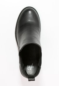 Botte en cuir noir avec une texture lisse, bout arrondi, panneaux latéraux élastiques et une poignée à l'arrière. L'intérieur présente un logo imprimé.