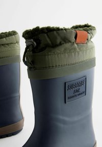 Bottes en caoutchouc bleues avec un col rembourré vert, un cordon ajustable, une bande texturée grise et un accent orange. Présente un logo à l'arrière.