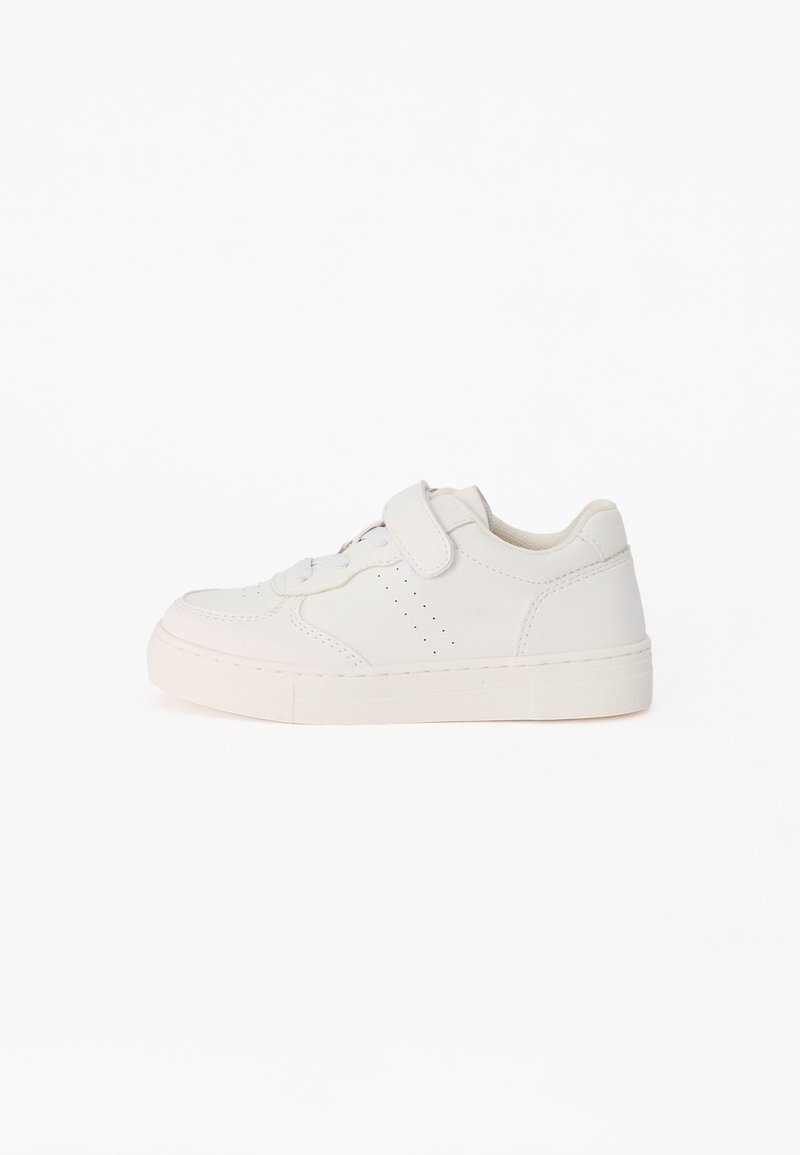 Baskets blanches basses avec une bande velcro et des lacets, détail perforé sur le côté et semelle en caoutchouc sur fond blanc uni.