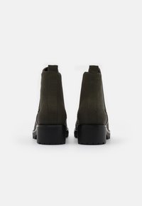 Stivali verde alla caviglia con una finitura in tessuto liscio, pannelli laterali elasticizzati e un alto tacco nero chunky. Design semplice senza motivi visibili.