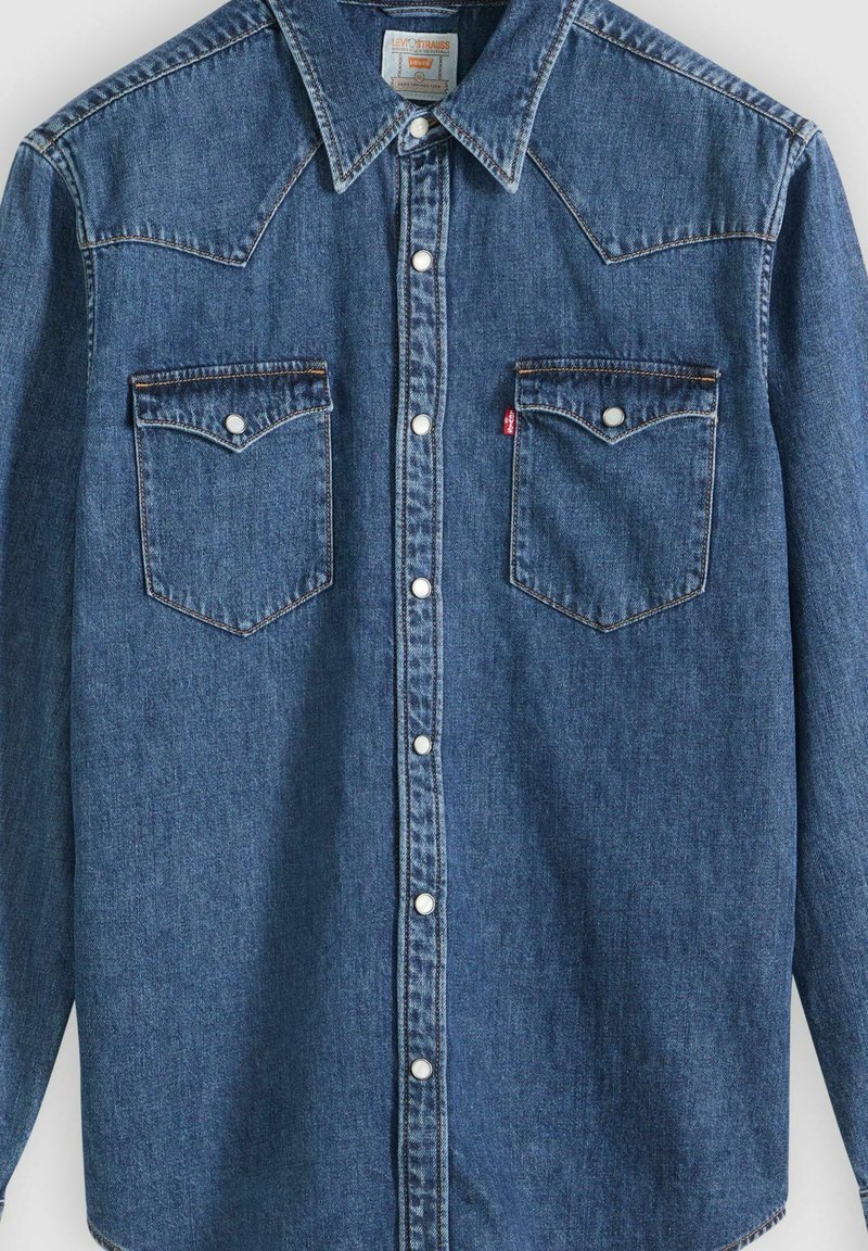 Jeans-Langarmhemd mit spitzem Kragen, Druckknopfverschluss, zwei Brustklappentaschen mit Knöpfen und sichtbarem Levi's-Label auf der Tasche.