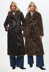 Kaksi pitkää takkia vierekkäin: toinen mustaa keinonahkaa turkiskauluksella ja toinen leopardikuvioinen vyötärönauhalla. Molemmissa on leveät kaulukset.