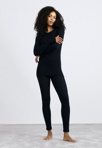 Zwarte long sleeve top en strakke leggings gemaakt van een soepel, rekbaar materiaal. Strakke ontwerp met een eenvoudige silhouette en lange mouwen.