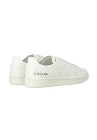 Sneakers bianchi in pelle con una finitura liscia, dettagli perforati sui lati e un accento distintivo sul tallone. Suola in gomma piatta.