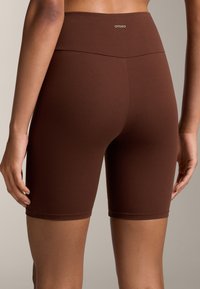 Barna, magasan derekú kerékpáros nadrág, rugalmas anyagból készült, sima felülettel és OYSHO logóval a deréknál.