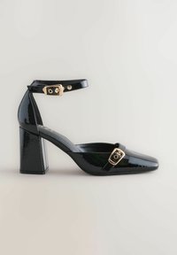 Black patent leather high-heeled shoe with a square toe, ankle strap, and gold buckle detail. Features a chunky block heel for support.
