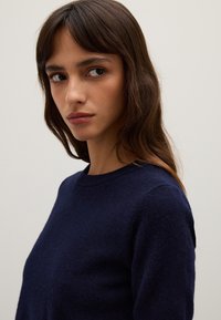 Maglione blu navy con scollo rotondo e tessuto morbido e texturizzato. Il maglione ha maniche lunghe, evidenziando un design casual.