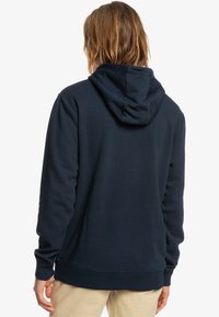 Navy blue hoodie made of soft fabric, featuring a large hood and ribbed cuffs. The design is simple with no visible patterns or graphics.