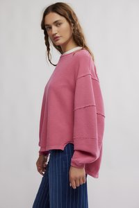 Ροζ φαρδιά ριμπ πλεκτή μπλούζα με ψηλό λαιμό και ακανόνιστο τελείωμα. Συνδυασμένη με ριγέ μπλε παντελόνια για ένα casual στυλ.