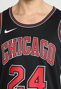 Maillot de basket-ball noir avec "CHICAGO" inscrit en lettres rouges audacieuses, numéro "24" en rouge, bordure blanche et logo Nike en blanc.