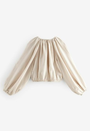 Blusa color crema con maniche lunghe e voluminose e polsini elasticizzati. Il tessuto è leggero con una finitura texturizzata e dettagli arricciati.