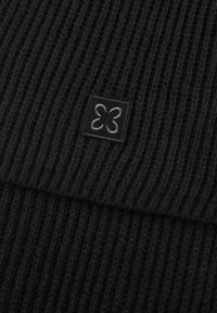 Zwarte gebreide beanie met een geribbelde textuur en een vierkant label met een grijs floraal patroon. Zacht, warm materiaal met een stevige pasvorm.