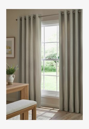 Beige strukturierte Vorhänge an einer Metallstange, die ein Fenster mit Gartenblick einrahmen, neben einem Holztisch mit einer weißen Vase mit Grünpflanzen.