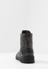 Bota de cuero de caña alta de la marca Black Diesel, con tacón visible y suela gruesa, exhibida sobre un fondo blanco liso.