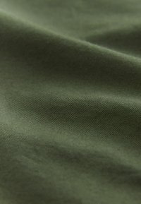 Tissu vert olive avec une texture lisse, présentant des motifs tissés subtils et un léger éclat, se drapant en douces vagues.