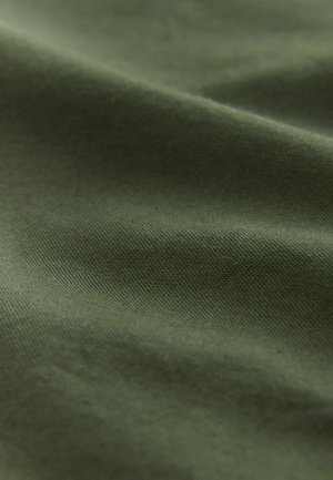 Olive rohelise värvusega kangas, millel on sile tekstuur, peened kootud mustrid ja kerge läige, ripub õrnade voldidega.