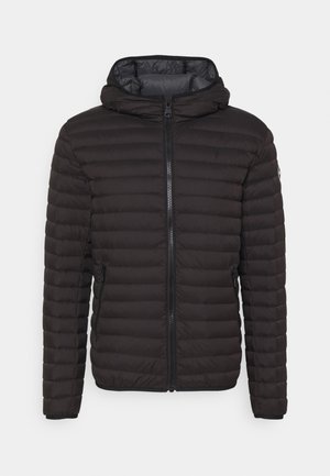 Veste matelassée noire, dotée d'un zip frontal, d'une capuche et d'une texture matelassée. Poches latérales avec des poignets élastiques.