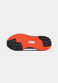 Semelle de chaussure avec motif de bande de roulement rugueux noir et orange, conçu pour l'adhérence et la durabilité sur diverses surfaces.