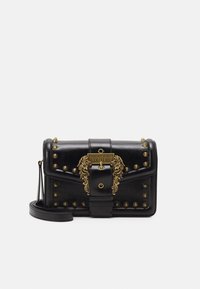 Svart läderaxelväska med gyllene nitar och en utsmyckad gyllene spänne graverad med "Versace Jeans Couture."