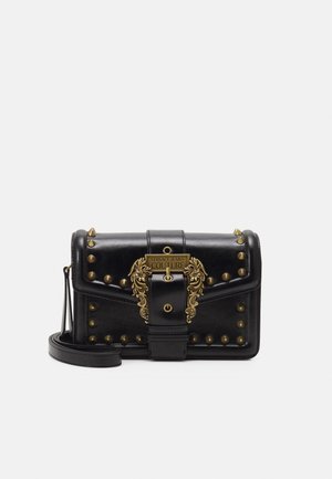 Sort læder skuldertaske med gyldne nitter og en udsmykket gylden spænde, der er indgraveret med "Versace Jeans Couture."