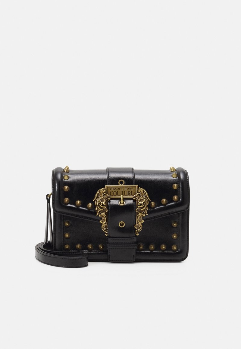 Svart läderaxelväska med gyllene nitar och en utsmyckad gyllene spänne graverad med "Versace Jeans Couture."