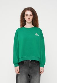 Πράσινο φούτερ με άνετη εφαρμογή, στρογγυλή λαιμόκοψη και ραμμένους ώμους. Διαθέτει μικρό κεντητό σχέδιο στο στήθος.