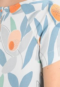 Short-sleeve top in lightweight fabric featuring a floral pattern with blue leaves and orange accents, textured finish, and a rounded neckline.