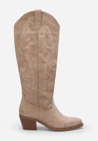 Botte de cowboy en suède beige avec un nez pointu, des coutures décoratives, et un talon carré moyen. Onglet de traction en haut pour un enfilage facile.