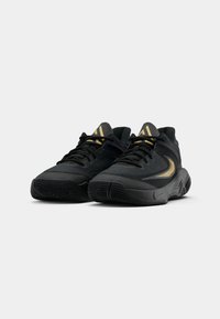 Et par sorte atletiske sneakers med guld accenter og sorte snørebånd, placeret side om side på hvid baggrund.