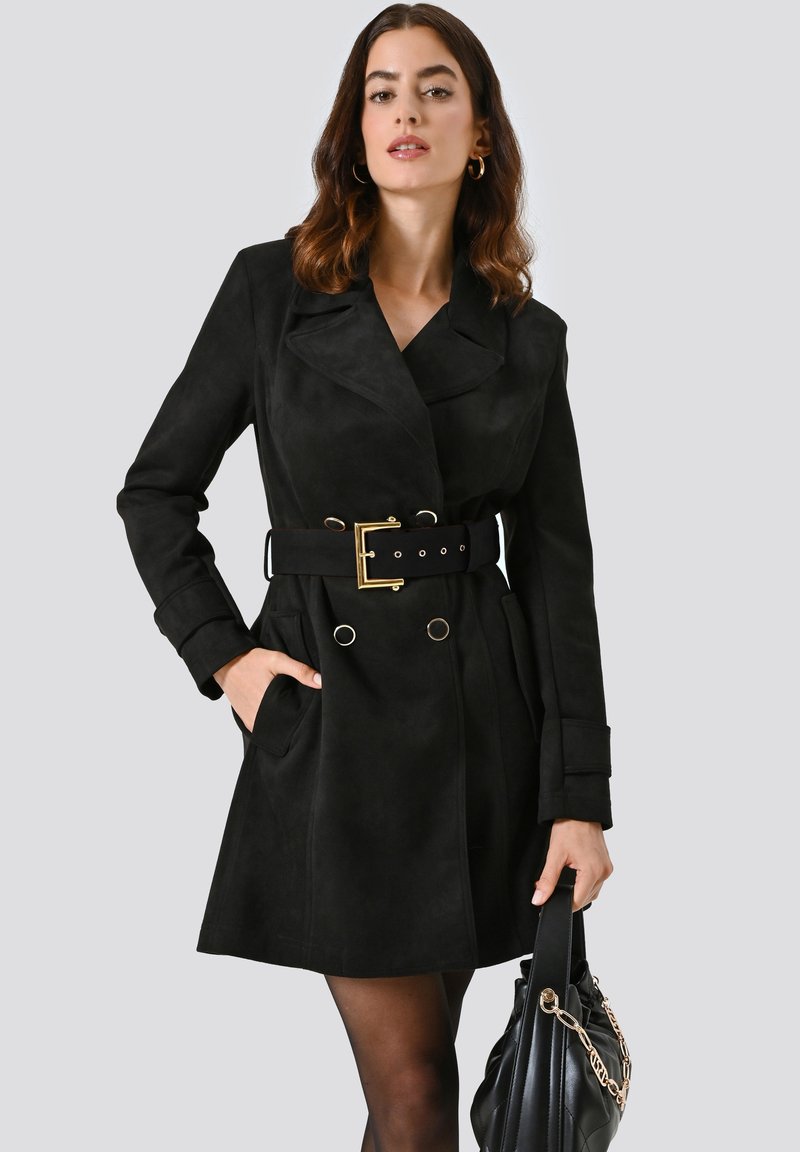 Cappotto in suede nero con ampio colletto, design doppiopetto, vita con cintura, due tasche laterali e dettaglio della fibbia della cintura in tono dorato.