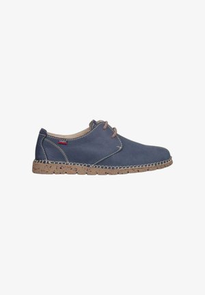 Zapato de cuero azul marino casual con suela texturizada beige, cordones beige, costuras blancas y una pequeña etiqueta de marca cerca del talón.