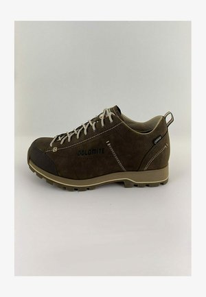 Braune Wildleder-Wanderschuhe mit verstärktem schwarzen Zehenkappe, beiger Gummisohle und neutralen Schnürsenkeln. Logo an der Seite und ein kleines rotes und grünes Etikett.