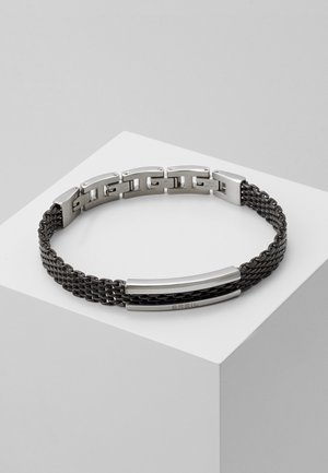 Brassard en métal avec un mélange de finitions mates et polies, présentant un design de chaîne tressée en argent et noir. Accentué par deux barres en métal élégantes.