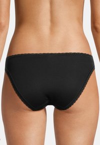 Slip in cotone nero con una texture liscia, caratterizzato da un delicato pizzo lungo i bordi e un design a vita media.