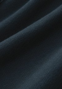 Tejido azul marino oscuro con una superficie ribeteada texturizada, que muestra finas líneas horizontales y una apariencia suave y tejida.