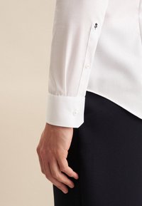 Witte shirt met een slim fit, voorzien van een knoopmanchet en een klein zwart rozenborduursel. Gladde stof, gestructureerd ontwerp.