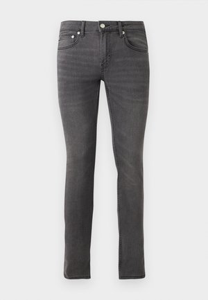 Sivi jean material s slim fit, z značilnim petim žepom, sprednjo gumbovno zaporo in blago teksturo po celotni površini.